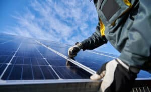 technician in work gloves installing stand-alone photovoltaic solar panel system